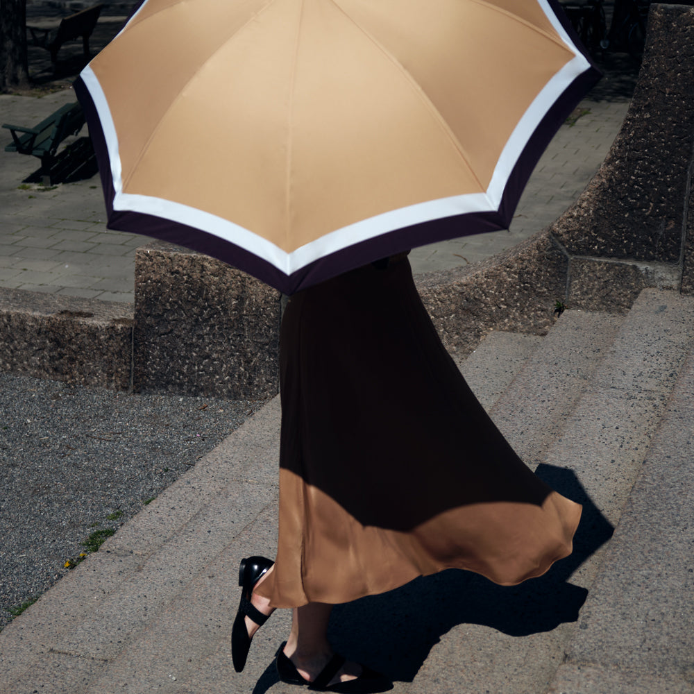 Diana umbrella comes with black leather cup handel. A elegant, premium umbrella with pattern in beige, white and black. Double layer canopy extends the life of the umbrella and fiberglass ribs and sturdy frames makes the umbrella wind resistant. No matter the forecast, the Diana umbrella is your stylish companion. | Harry Rain